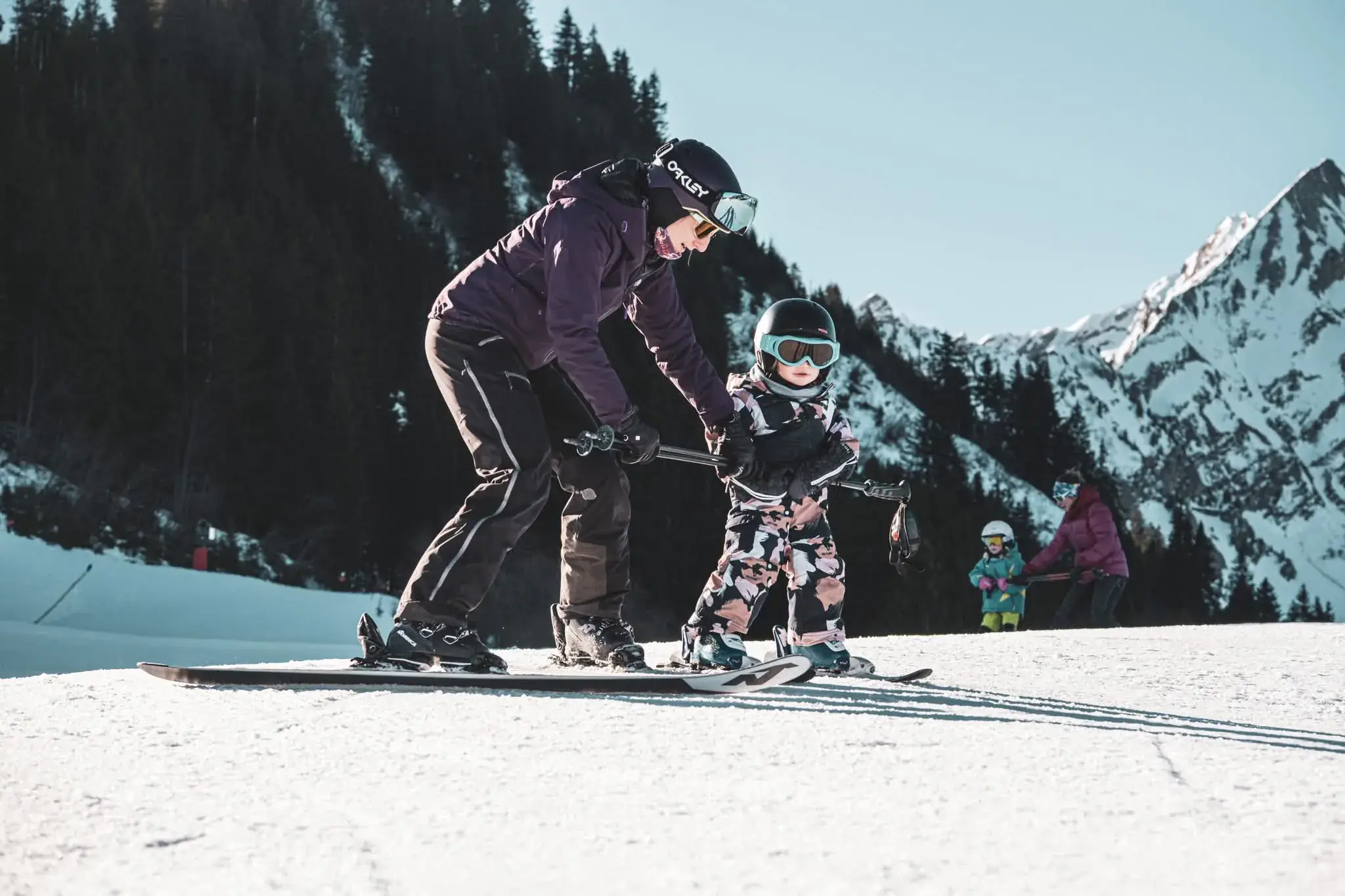 Sofia, penchée derrière une toute petite skieuse, la guide sur une pente douce.